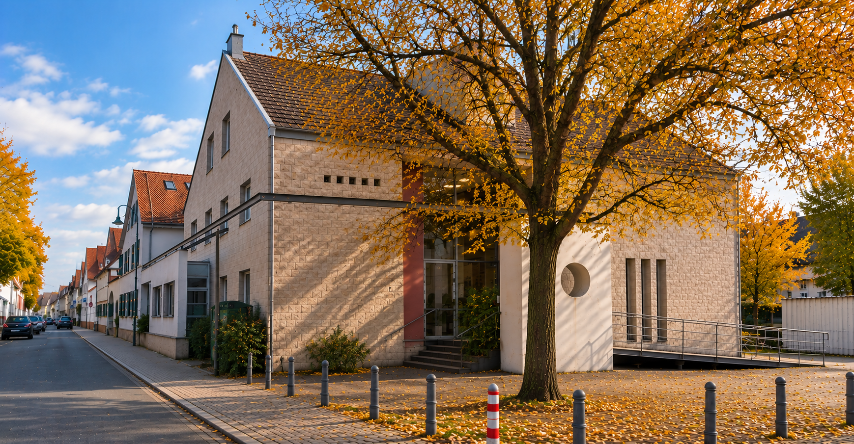 Teilweise durch einen Baum verdeckter Gebäudeeingang im Herbstlicht